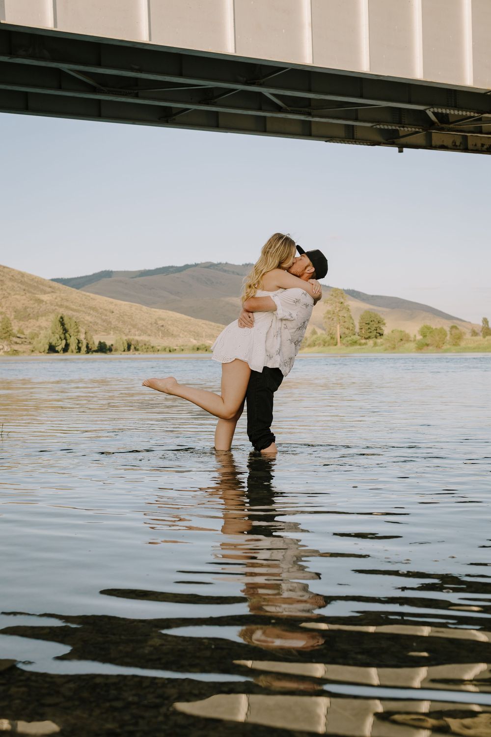 Romantic water photoshoot with couple in lake against mountain landscape.