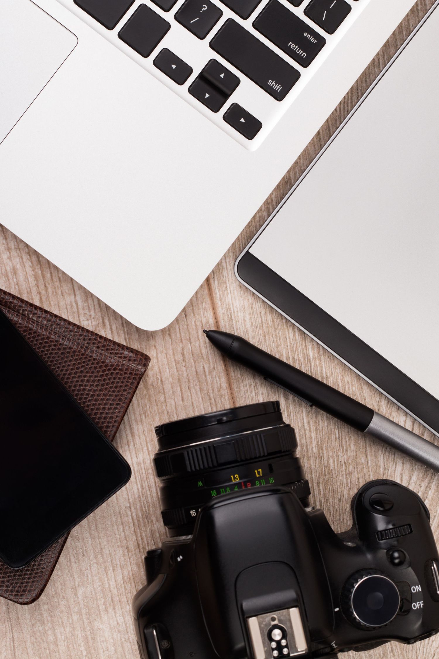 Professional camera setup with laptop and accessories on wooden surface.