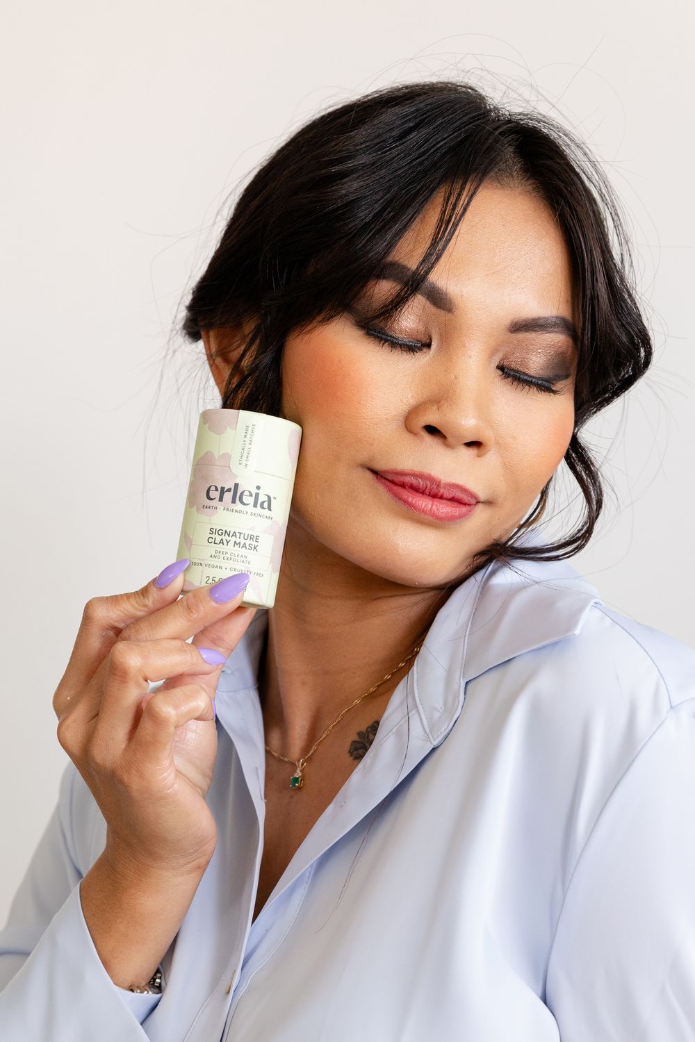 woman standing with roll on lotion to her face lovingly
