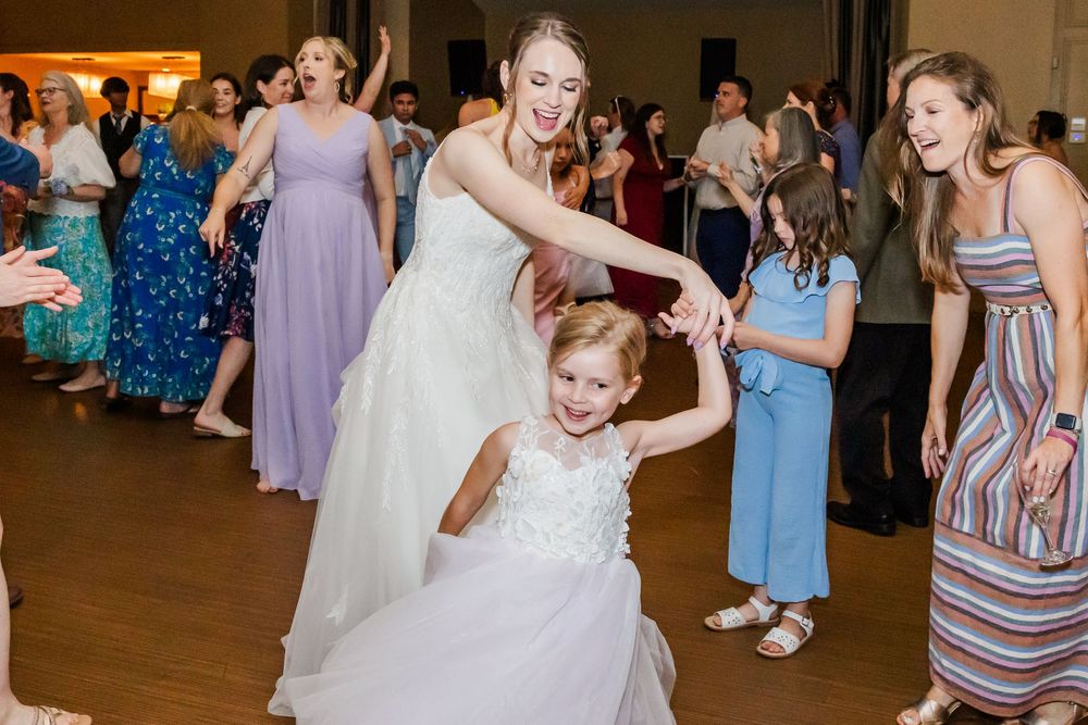 Guests in formal attire dancing and celebrating during a wedding reception on a dance floor.