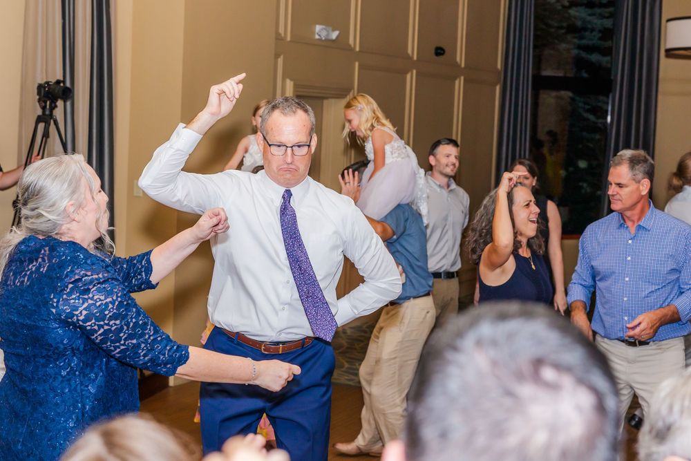 People dancing and celebrating at a party event in an indoor venue with guests in formal attire.