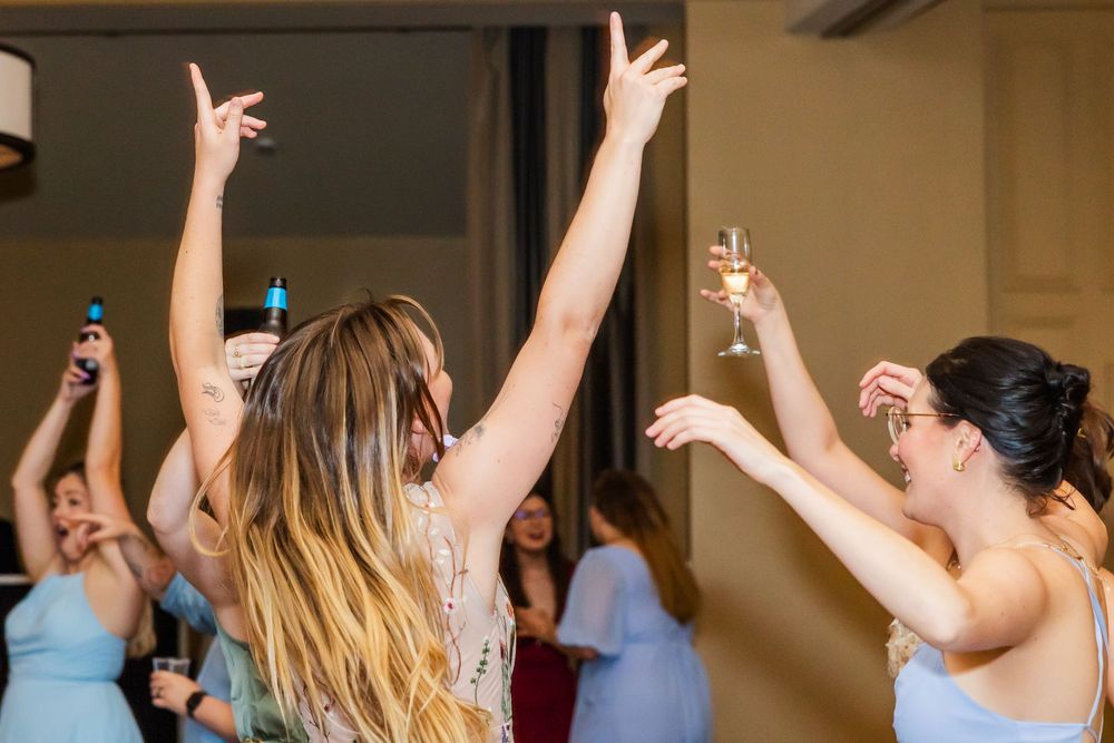 Celebratory moment at a party with people raising their glasses and hands in the air while dancing together.
