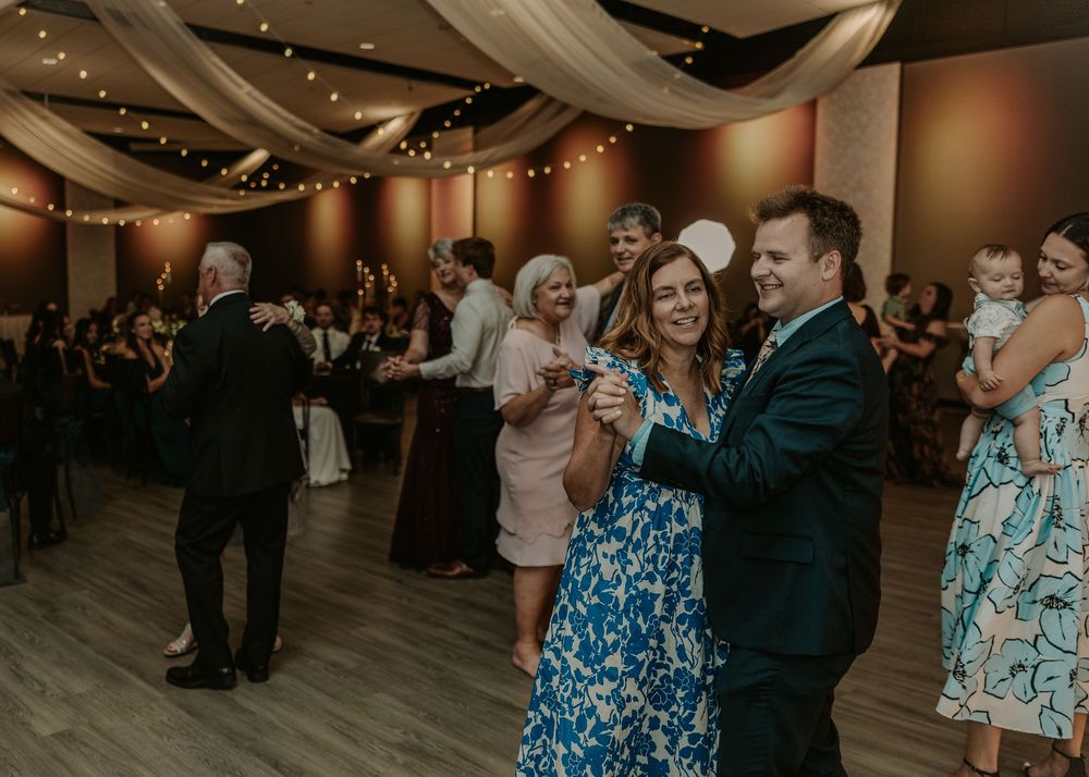 Guests dancing on an elegantly lit dance floor at an indoor wedding reception venue.