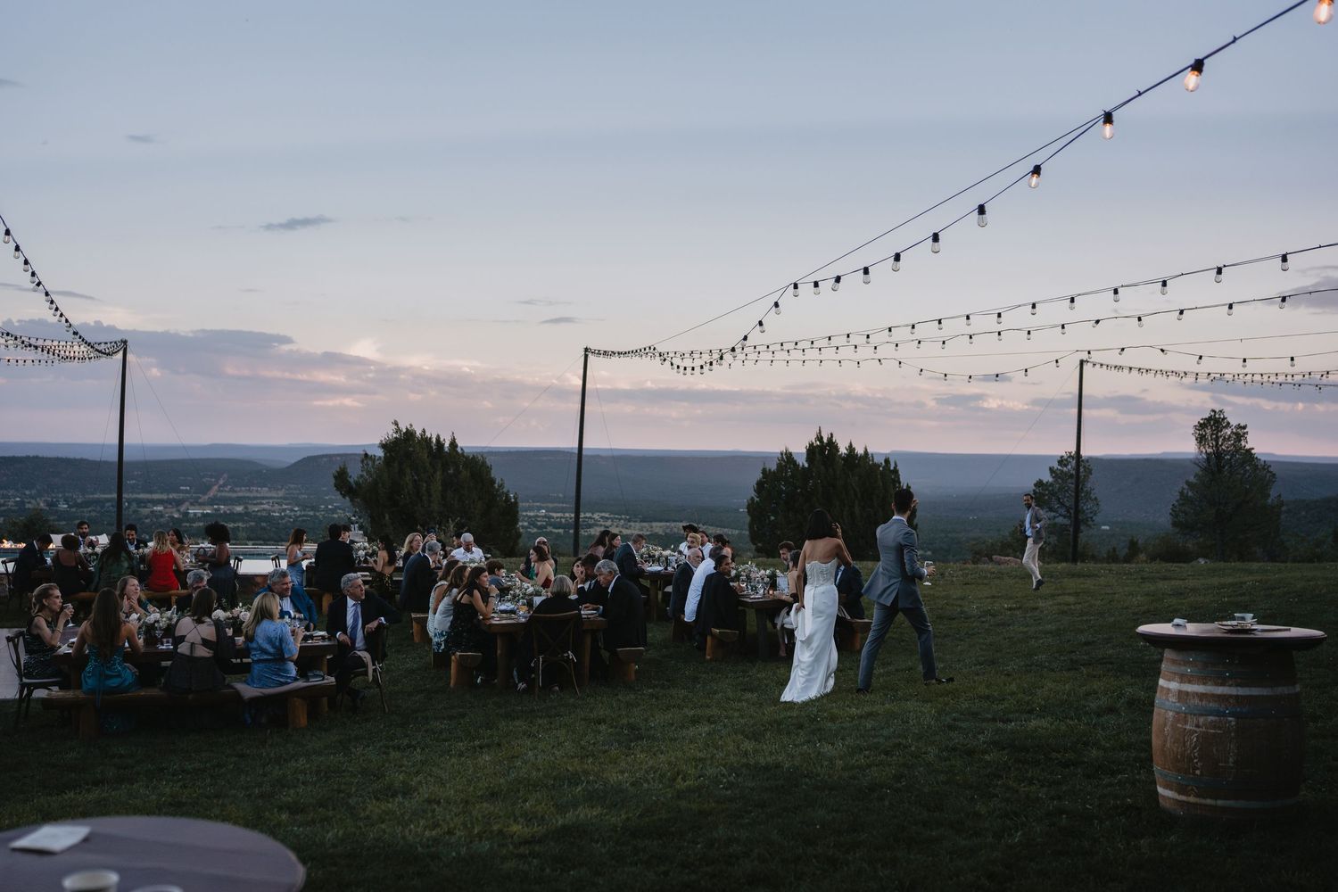 Couples first dance at an outdoor wedding reception under string lights at dusk.cinematic wedding photographer new mexico
