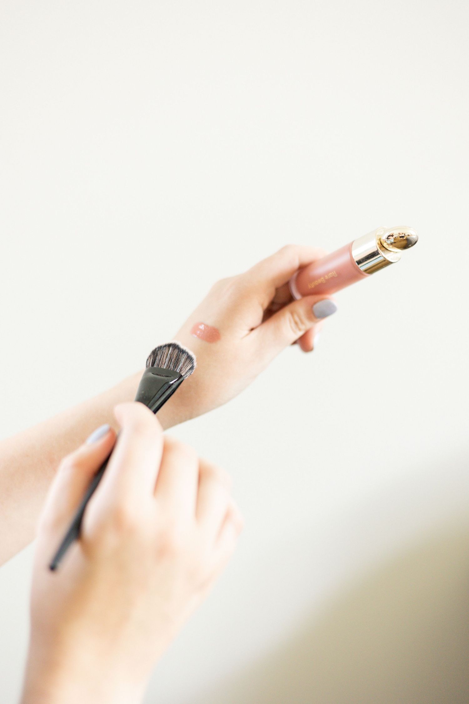 Makeup artist hands close up testing out a color with a brush on her wrist.