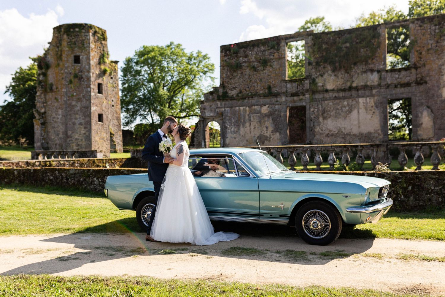 Mariés posant devant une voiture de collection devant un château des Deux-Sèvres, reportage mariage élégant et prestigieux près de Niort.