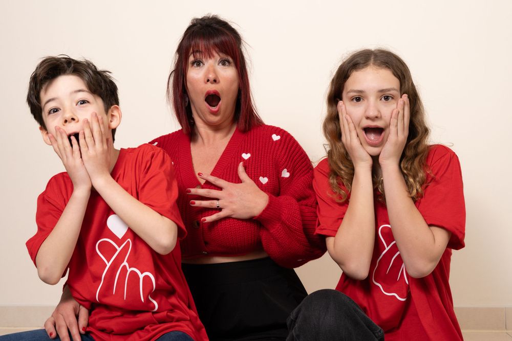Trois personnes en chemises rouges faisant des expressions surprises sur fond blanc.