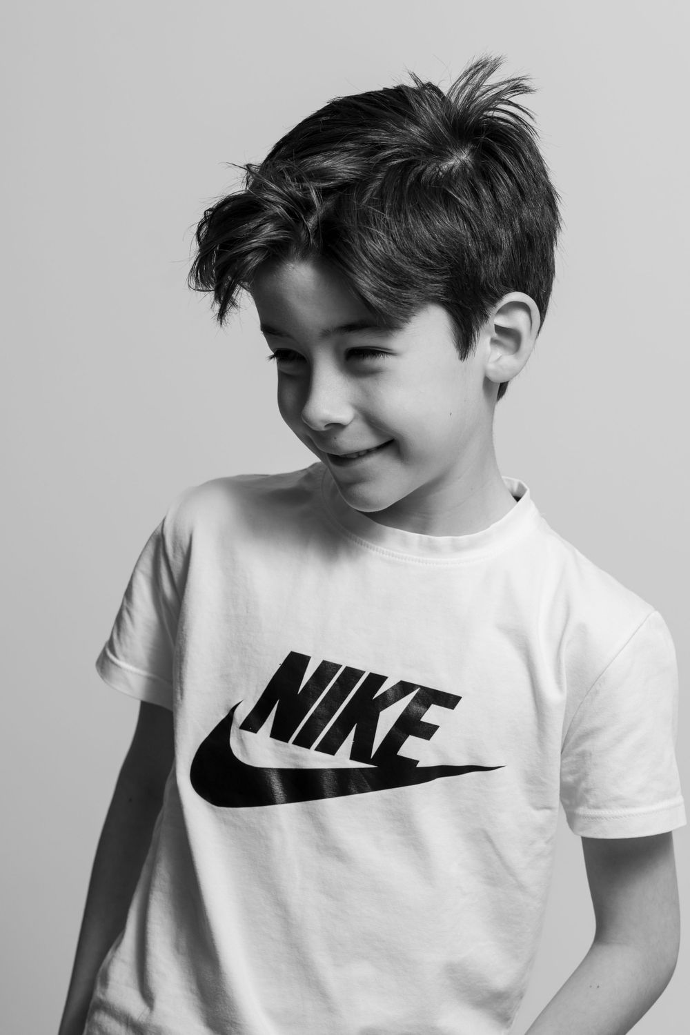 Garçon en t-shirt Nike blanc souriant dans un portrait en noir et blanc.