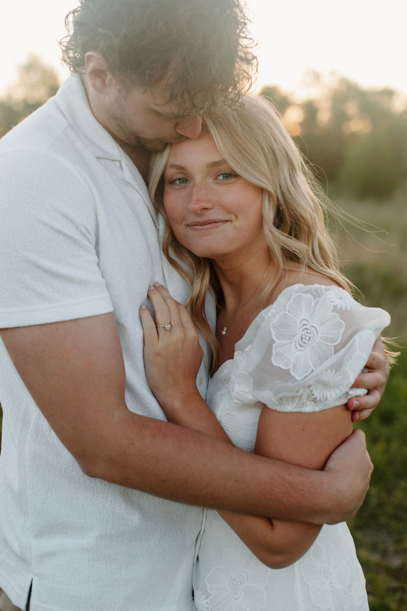 Couple embracing during Grand Rapids engagement session. He is kissing her forehead.