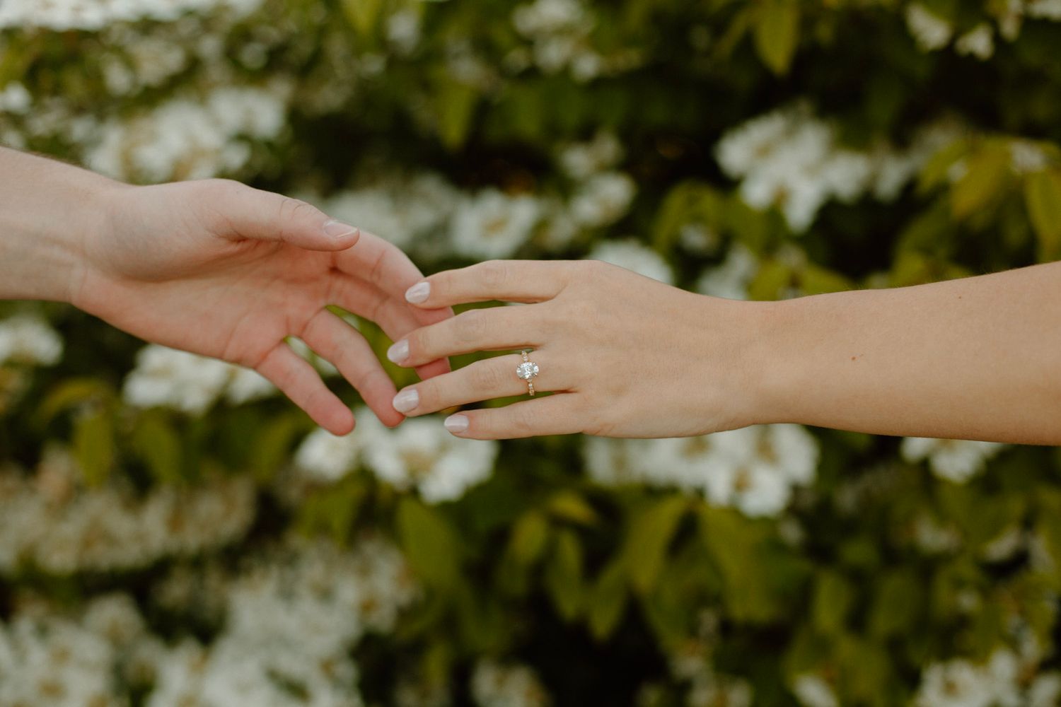 Hands reaching for each other displaying engagement ring during engagement session.