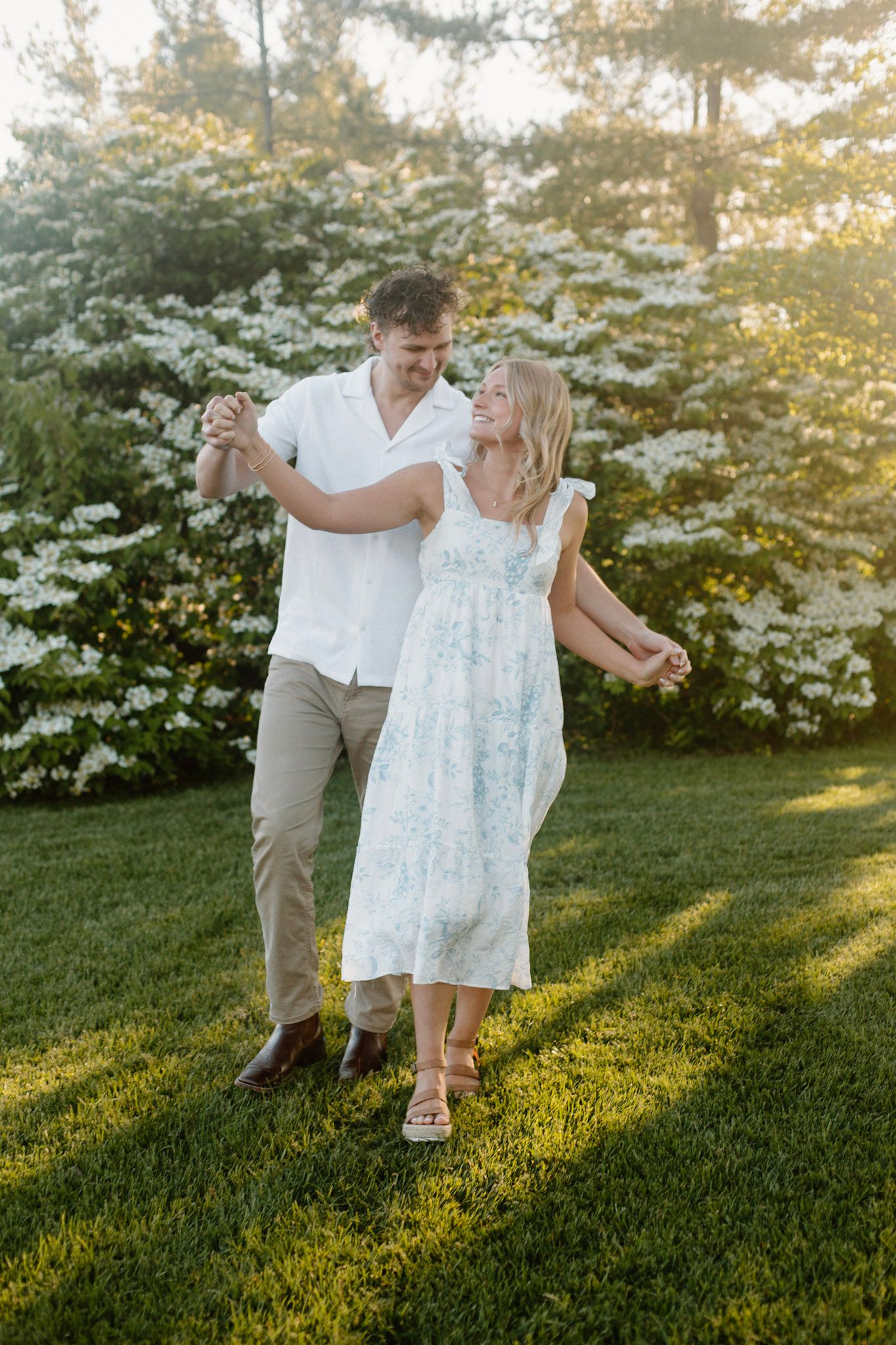 Couple walking in front of a flowering bush during their engagement session at Millennium Park in Grand Rapids MI.