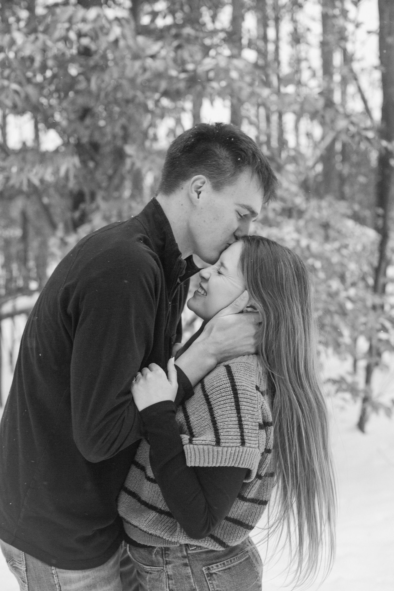 Couple embracing during their winter engagement session in Holland, MI.