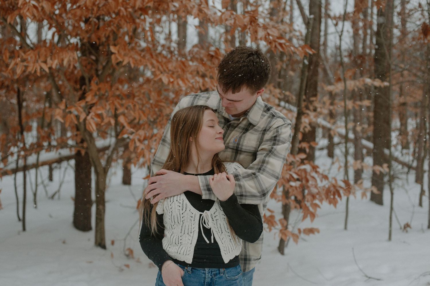 Couple embracing during their winter engagement session in Holland, MI.