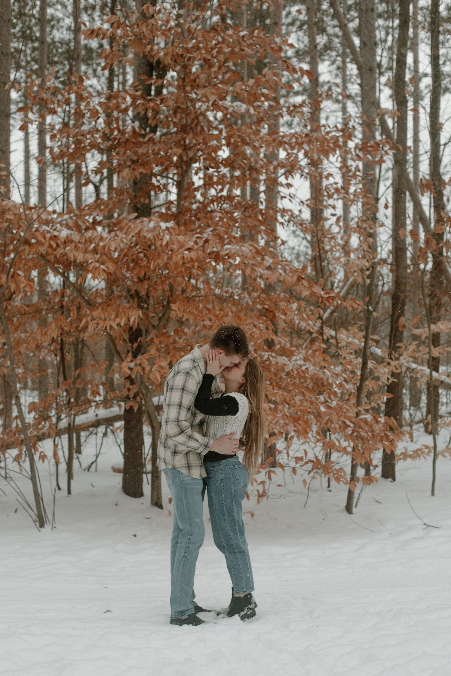 Couple embracing during their winter engagement session in Holland, MI.