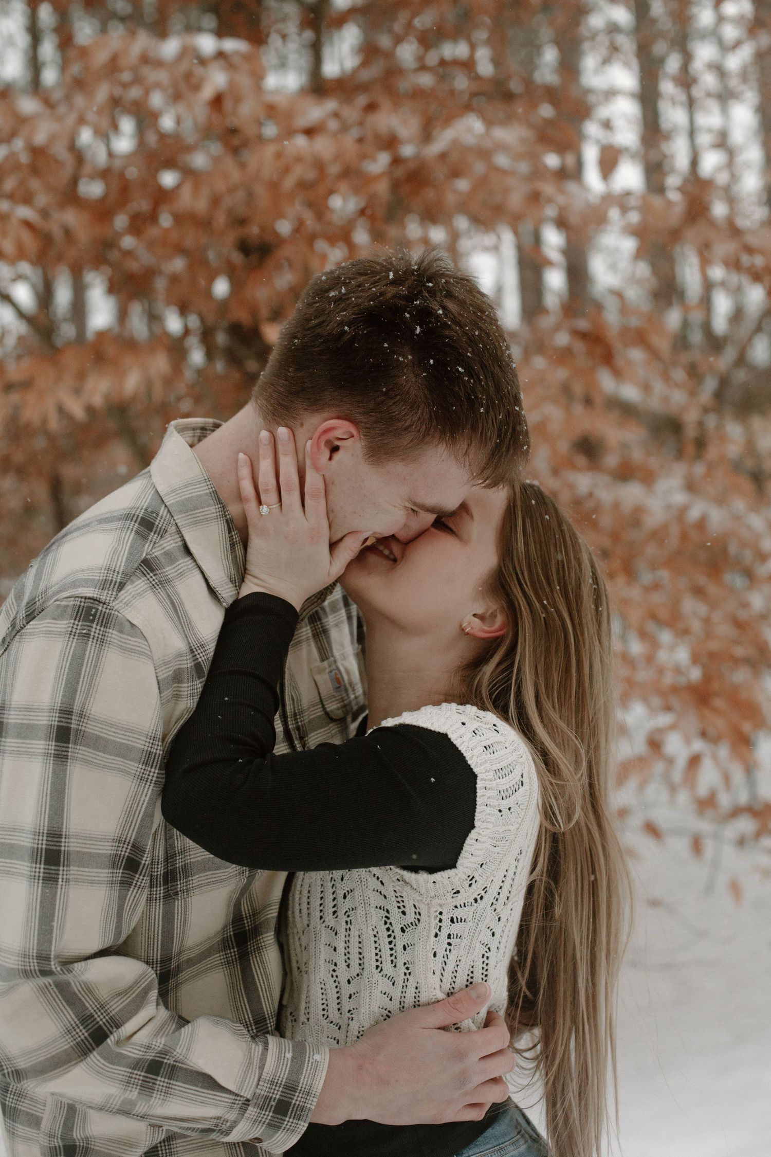 Couple embracing during their winter engagement session in Holland, MI.