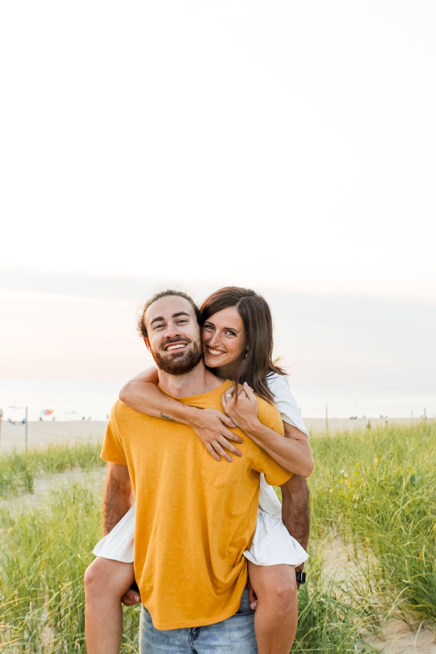 Couple engagement session in Holland, MI and he is giving her a piggy back ride.