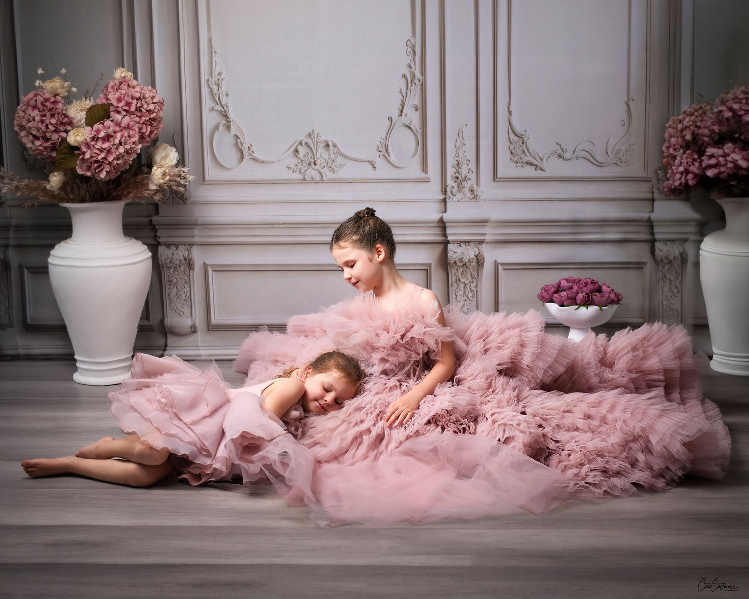 Example of the antique white wall backdrop in use. Sisters sitting in matching pin couture gowns.