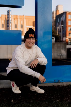 Someone in white sits by large blue letters in an urban setting.