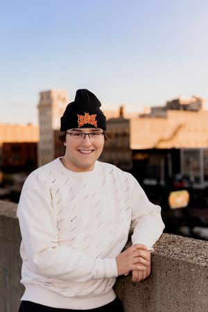 Person in casual attire poses against urban backdrop during golden hour.