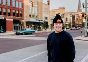 Person poses on city street with traffic lights and buildings visible.
