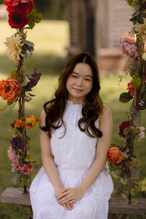 A white floral swing decorated with colorful roses and flowers creates a whimsical garden setting.