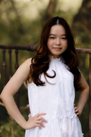 A white sleeveless dress stands out against a soft, natural outdoor background.