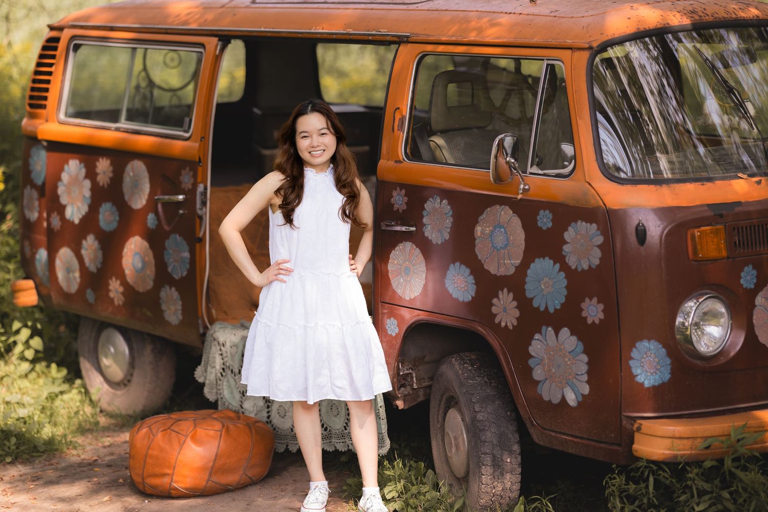 A retro orange VW van decorated with flower decals creates a vintage photography backdrop.