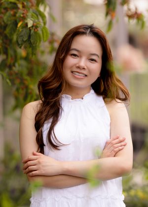 Casual outdoor portrait with crossed arms wearing a white ruffled collar dress.