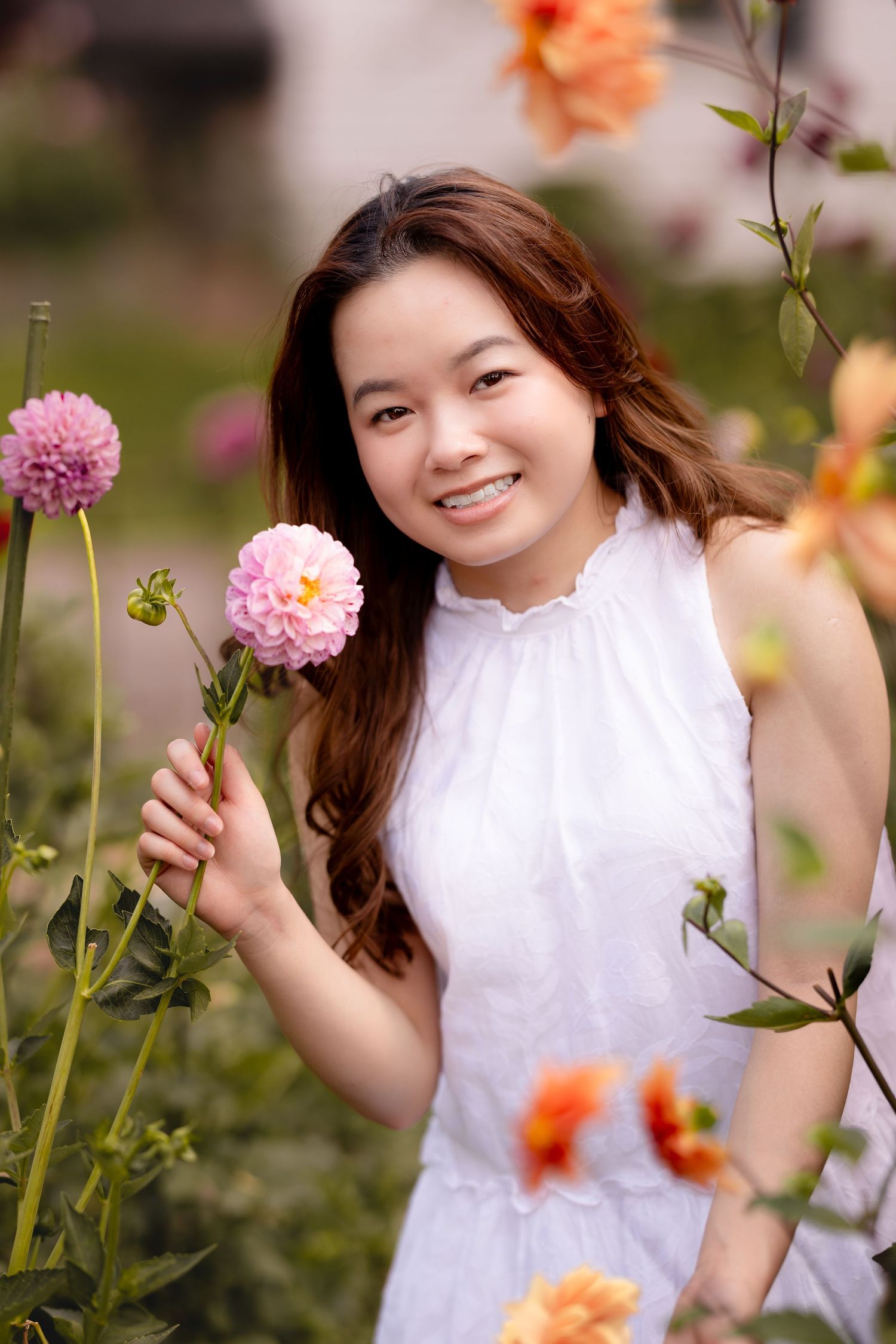 Garden portrait with pink dahlia flowers and orange blooms in soft focus.