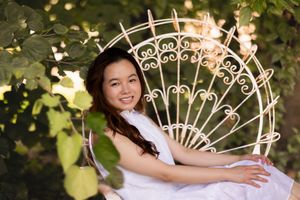 White dress portrait on decorative garden bench with ornate metalwork.