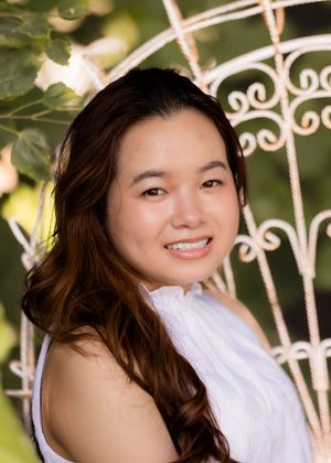 Garden portrait against white ornamental fence with sunlit foliage.