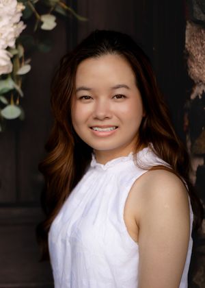 Studio-style portrait with floral decorations against dark background.
