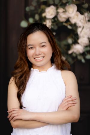 A person wearing a white sleeveless top poses against a dark floral backdrop in a series of portraits.