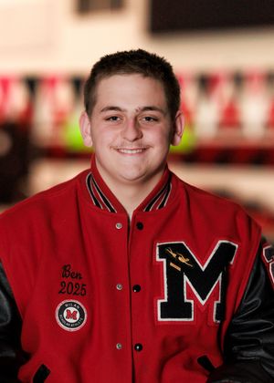 High school athlete in red and black varsity letter jacket poses for portrait.