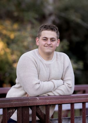 Casual outdoor portrait on wooden bridge wearing cream sweater in natural setting.