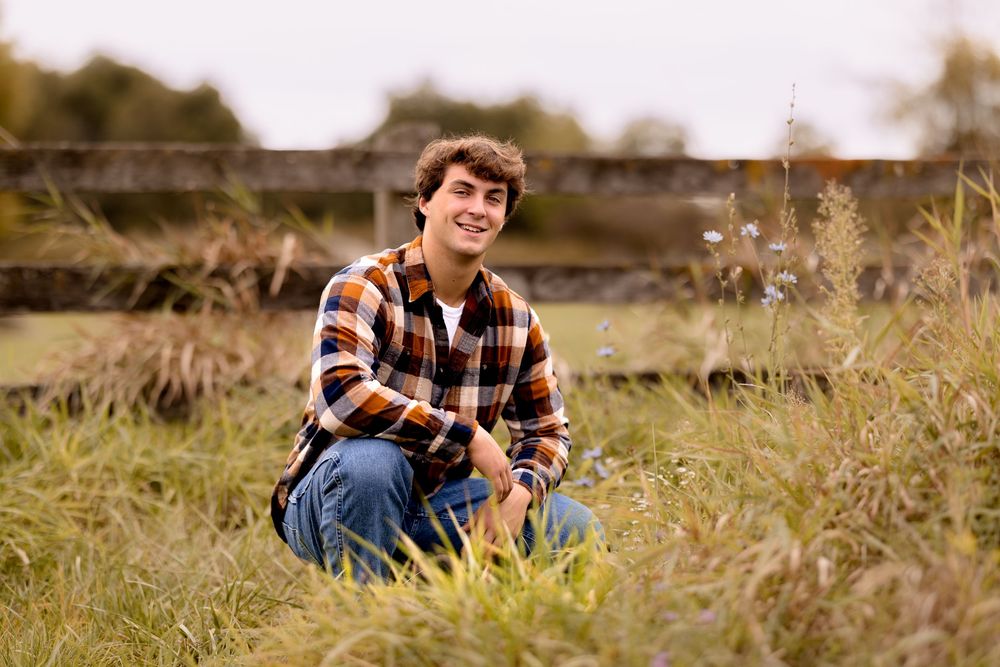 A casual outdoor scene with someone in a checkered shirt sitting in tall grass.