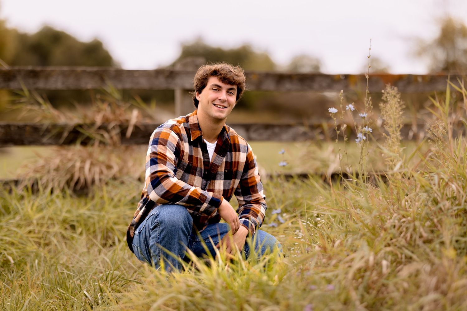 A casual outdoor scene with someone in a checkered shirt sitting in tall grass.