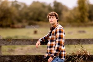 A person in plaid relaxes outdoors against a rustic background.
