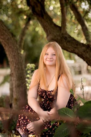 Natural outdoor portrait session under tree branches with dappled sunlight.