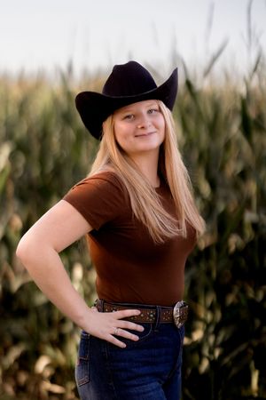 Western-themed photoshoot with cornfield backdrop and cowboy hat styling.