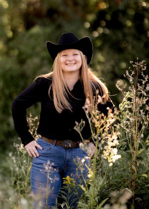 Western style portrait in a field with wildflowers featuring denim and black attire.