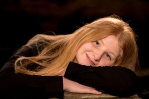 Artistic studio portrait with flowing blonde hair against dark background.