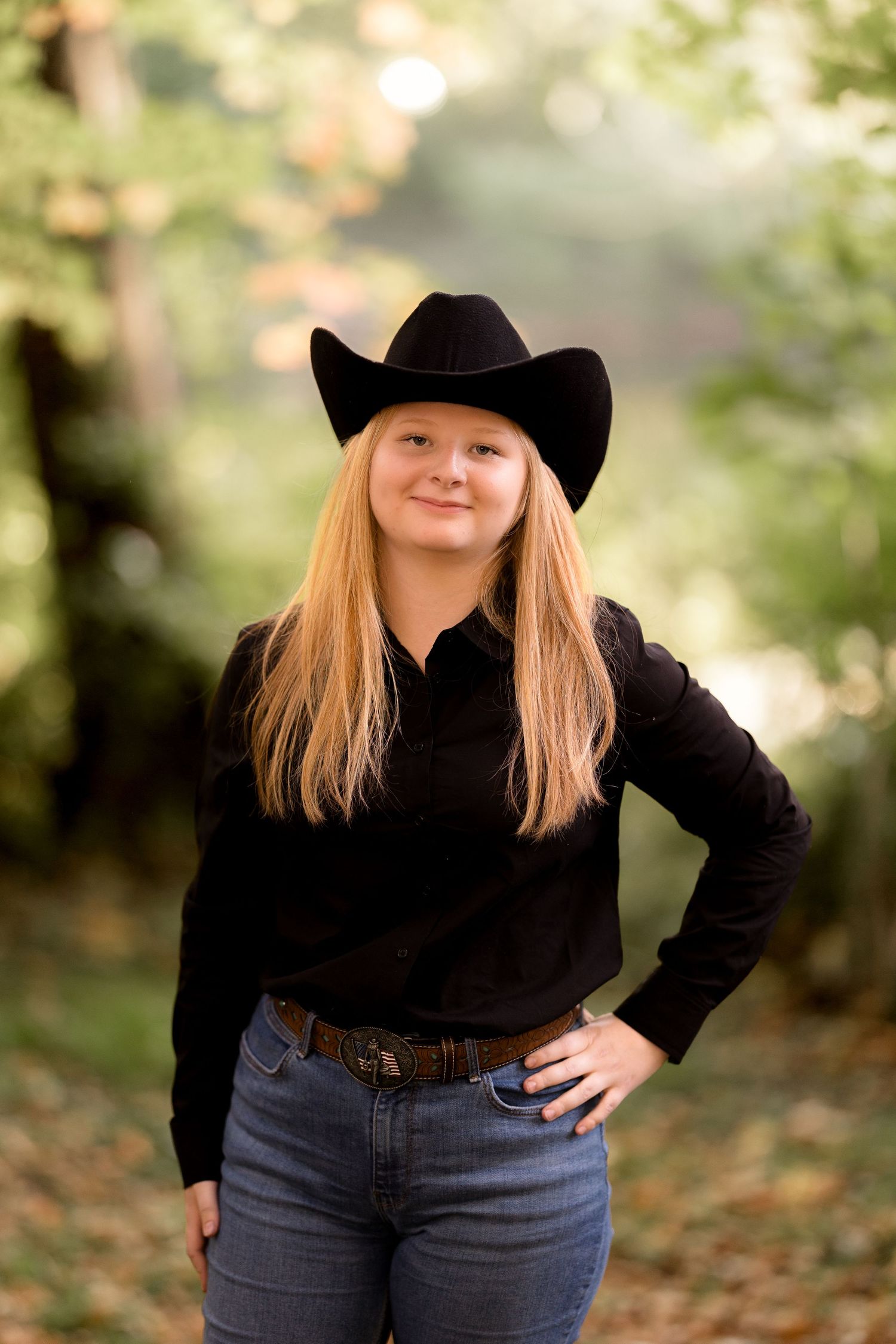 Casual western fashion shoot with black cowboy hat and turtleneck among fall foliage.