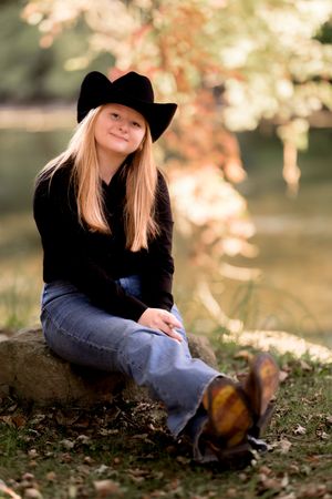 Relaxed outdoor portrait on fallen leaves wearing western attire and boots.