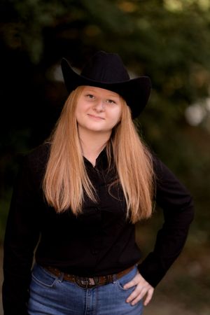 Western-inspired fashion portrait with black hat and turtleneck against natural backdrop.