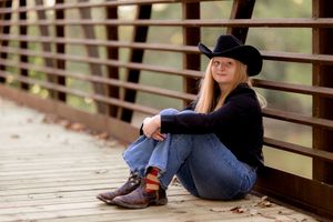 Casual portrait on wooden bridge wearing western hat and casual denim outfit.