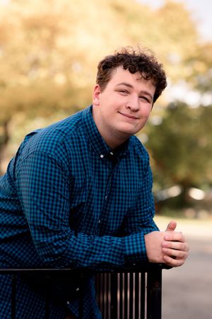 Casual portrait series showing person in blue checkered shirt leaning on railing.