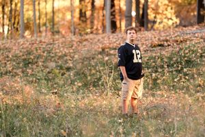 Person in sports jersey walking through a wooded area with fall colors.