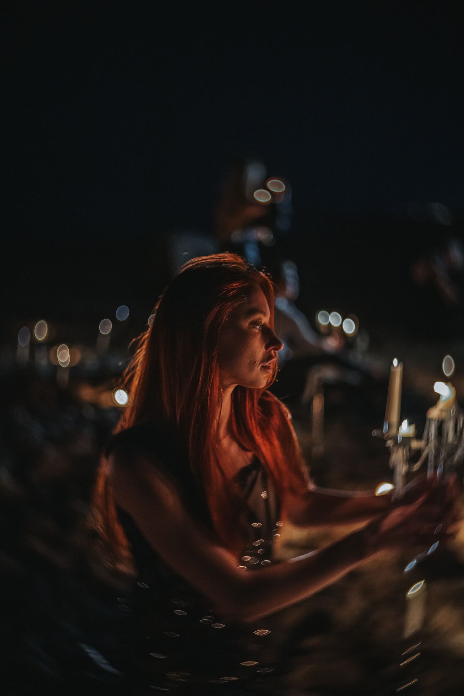 A person with red hair illuminated by candlelight creates a moody atmospheric portrait series. Shot with New Petzval lens.