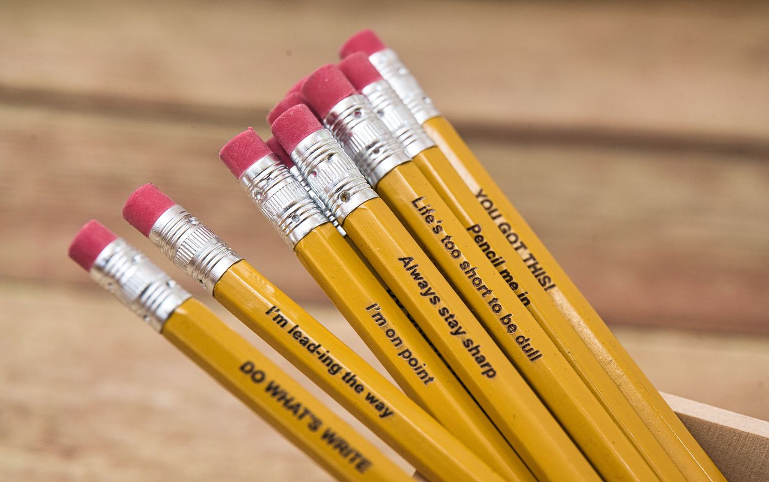 Yellow number 2 pencils with pink erasers lined up in a row.